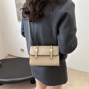 Sac bandoulière minimaliste beige avec boucle dorée présenté sur le dos d'un mannequin