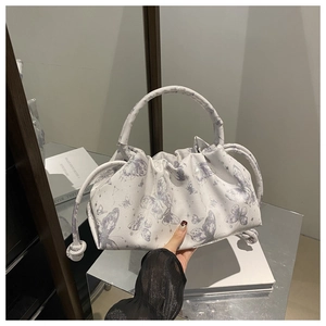 Close-up of white pleated cloud bag featuring grey butterfly prints and knotted ring handle