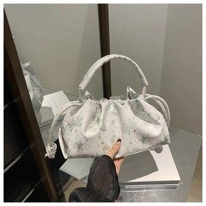 Detail of white drawstring bag featuring green butterfly prints and pleated texture