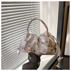 Close-up of white pleated tote bag with butterfly prints and elegant knot details