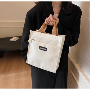 Close-up of minimalist beige canvas tote with brown straps and fashion label detail