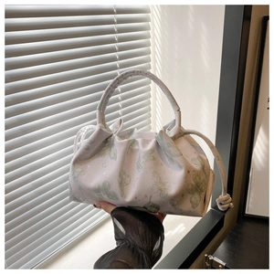 Detail of white pleated handbag with butterfly print and round handle in soft sunlight