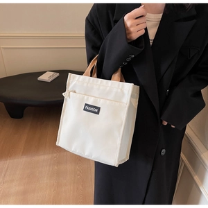 Detail of white canvas tote bag with FASHION label and front zipper pocket detail