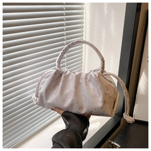 Close-up of pink butterfly pattern and pleated texture on a soft shoulder bag