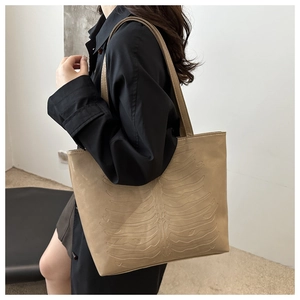 Macro detail of large beige leather tote bag featuring unique 3D bone relief texture