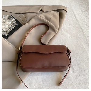 Détail du sac à bandoulière marron foncé avec rabat ondulé et boucles en métal doré