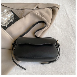 Détail d'un sac à bandoulière noir avec rabat ondulé et boucles métalliques dorées chic