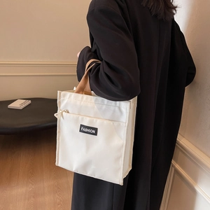 Minimalist white canvas handbag with brown straps and front pocket shown on a model