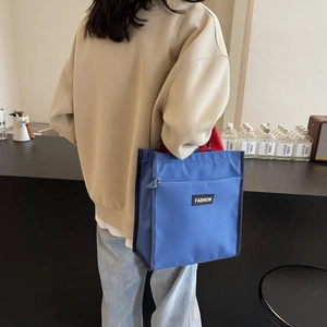 Minimalist blue canvas handbag with red handles and Fashion label shown in a cafe setting