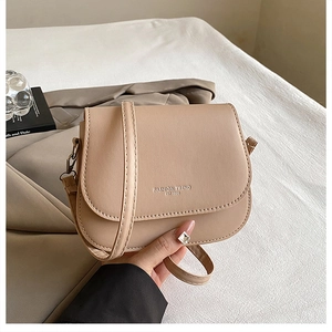 Detail of beige saddle bag with Fashion Trend embossing and adjustable leather strap