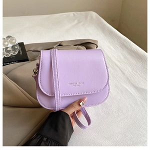 Detail of light purple leather saddle bag with Fashion Trend lettering and adjustable strap