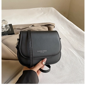 Detail of black saddle bag with FASHION TREND lettering on white textured background