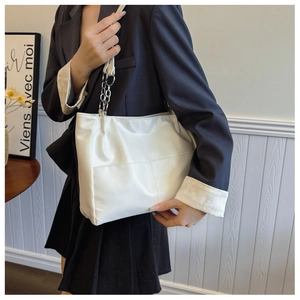 Detail of white faux leather tote bag with silver chain strap and stylish stitching