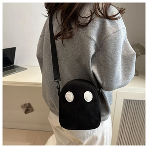 Détail d'un sac fantôme en velours côtelé noir montrant la texture et les yeux cartoon