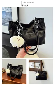 Macro detail of black PU leather tote bag with silver metal chain and plush charm