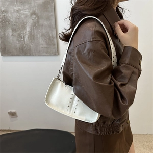 Vintage weiße Schultertasche aus Kunstleder mit silbernen Nieten an einem Model