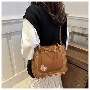 Détail du sac cabas en peluche avec cuir caramel et broderie de papillon rose