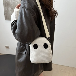 Sac bandoulière blanc en velours côtelé avec yeux fantôme sur mannequin en cuir