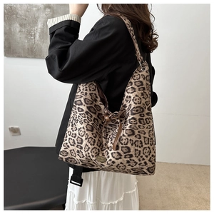 Close-up of leopard print tote bag with brown leather bow and handmade metal plate