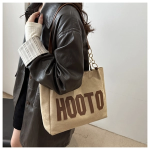 Detail of khaki tote bag with HOOTO patch and leather gold chain shoulder strap