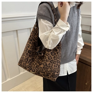 Detailed side view of a large leopard print canvas tote bag worn on shoulder