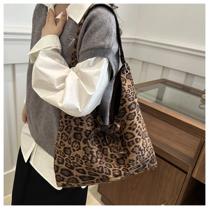 Detail of a large leopard print suede tote bag worn as a shoulder bag in a modern interior