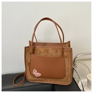 Vue détaillée du sac cabas en peluche marron avec poche en cuir et broderie papillon rose
