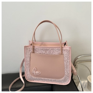Gros plan détaillé du sac cabas en peluche rose avec poche en cuir et broderie papillon blanc