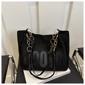 Detail of black suede tote bag featuring Hooto embroidery and gold chain straps