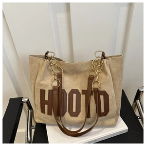 Detail of canvas tote bag with brown HOOTD patch and leather metal chain straps