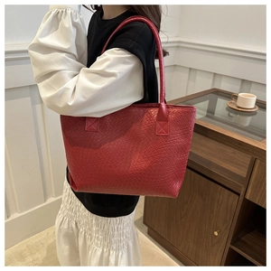 Close-up of red large tote bag with iconic woven leather texture and slender shoulder straps