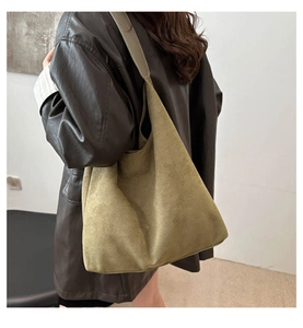 Detailed close-up of olive green corduroy tote bag worn with a brown vintage leather jacket