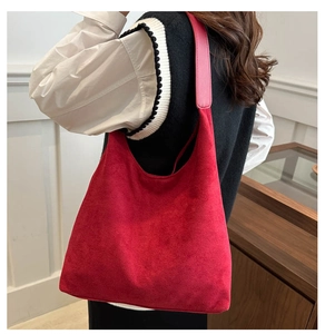 Macro detail of deep red suede tote bag texture with smooth leather shoulder strap