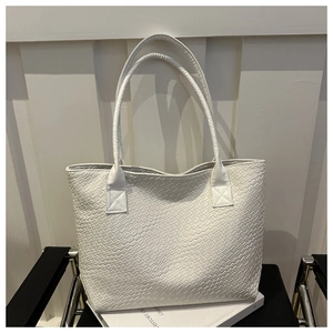 Detailed view of white woven texture and shoulder straps on a stylish large tote bag