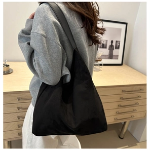 Rear view of model wearing a large black minimalist hobo tote bag in a casual indoor setting