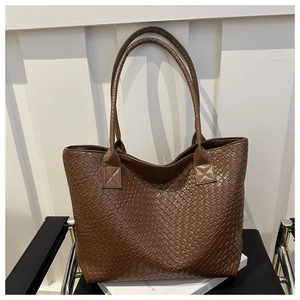 Close-up of the brown woven leather texture and handle detail on a large tote bag