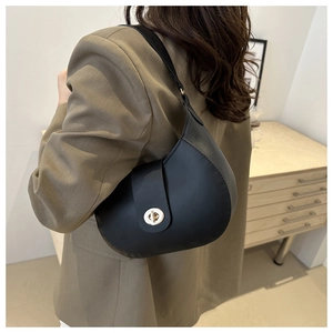 Detail of a black hobo bag with a gold metal clasp, worn with a khaki oversized blazer