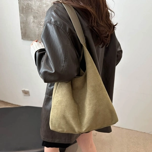 Olive green suede tote bag in large hobo style worn by a model in a minimalist setting