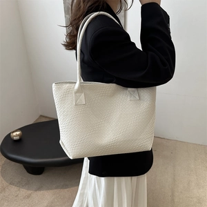 Ivory white tote bag with crocodile embossed texture in a minimalist indoor setting