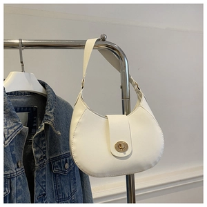 Detailed shot of warm white crescent bag with golden twist lock on denim jacket backdrop