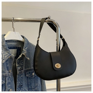 Detail of a black matte leather hobo bag with gold twist lock hanging on a metal rack