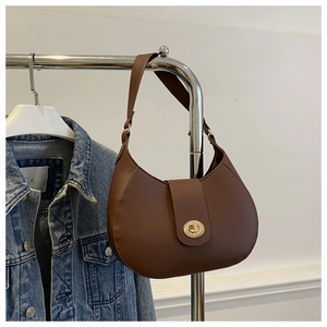 Detail of dark brown crescent bag featuring a golden metal twist lock and smooth texture