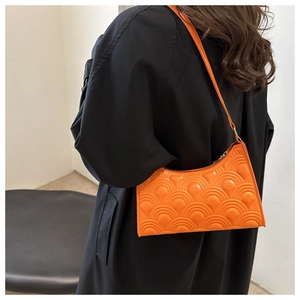 Detail of orange embossed fish scale texture on fashion underarm shoulder bag
