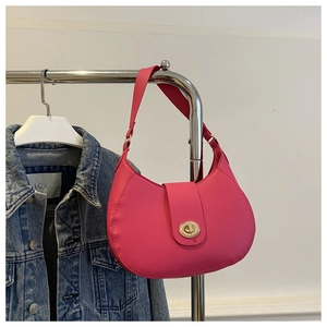 Macro detail of magenta crescent shoulder bag featuring a round golden twist lock closure