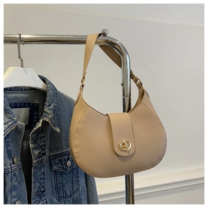 Detail of beige crescent underarm bag with gold rotary lock and smooth matte leather