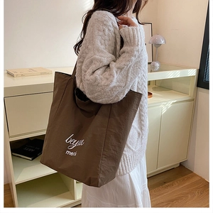 Detailed side view of a large brown leopard tote bag with white cursive lettering