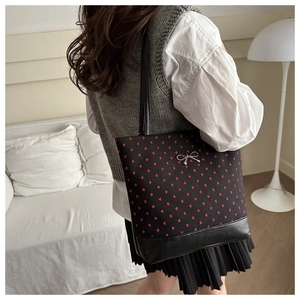 Detailed view of black polka dot tote bag with red hearts and silver bow buckle
