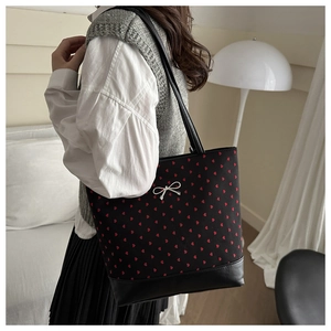 Close-up of black polka dot bucket bag with red heart pattern and silver bow detail