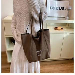 Close-up of leopard print lining and white letter print on a brown nylon tote bag