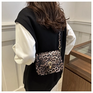 Détail du sac à bandoulière léopard avec boucle fer à cheval dorée sur l'épaule du modèle